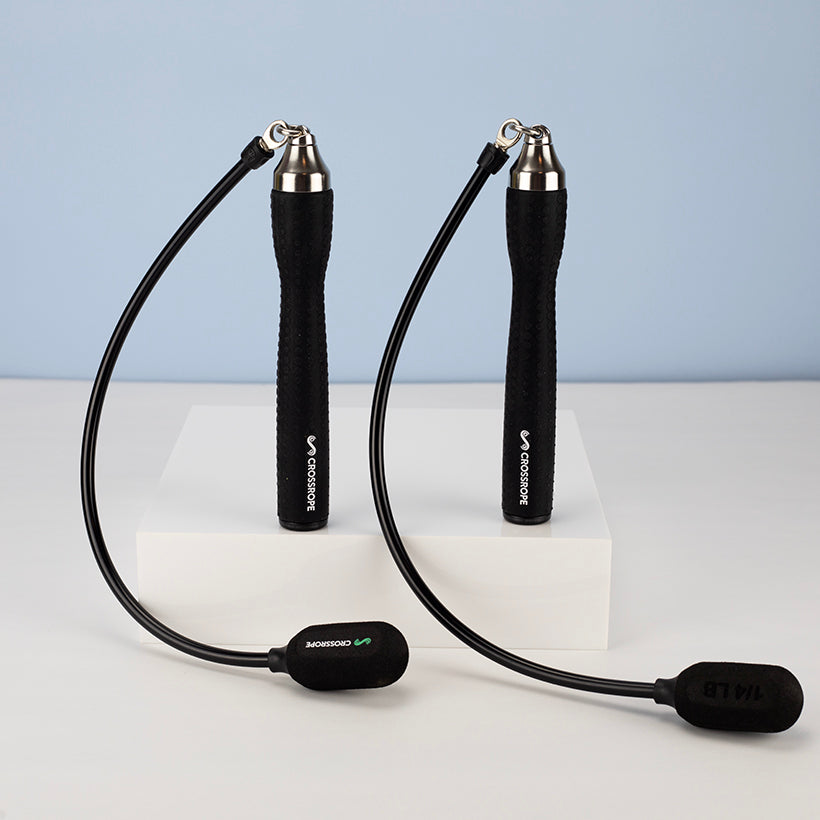 Ropeless One Black (ropeless) jump rope with silver ends on a white platform against a light blue background