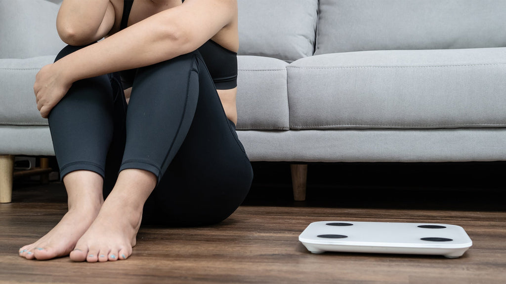 Overwhelmed person sitting next to workout equipment showing the psychological struggle with exercise