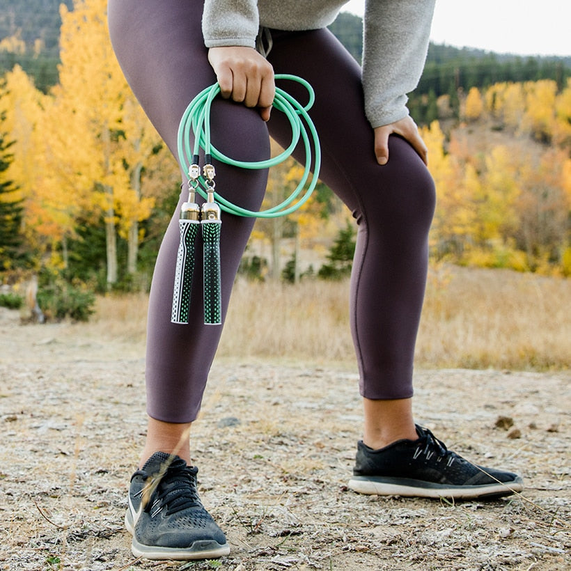 Starter Jump Rope Set* Woman outside in running shoes holding 1/4 LB ropes with Slim handles