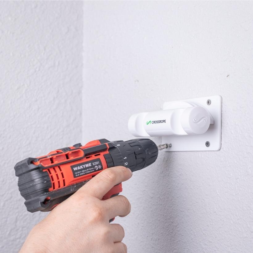 Get Lean + Get Strong Wall Mounts Person drilling a jump rope wall mount to secure it to the wall. 