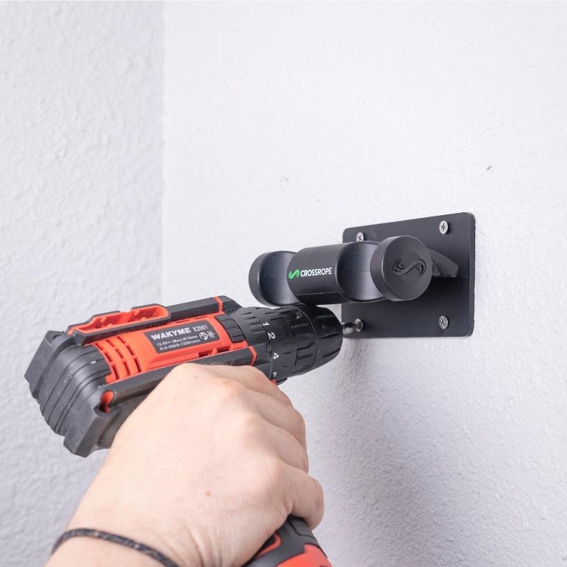 Get Strong Wall Mount Person drilling a jump rope wall mount to secure it to the wall. 